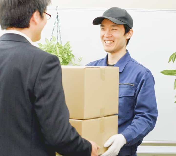 配送員が笑顔で段ボール箱を受取人に手渡している様子