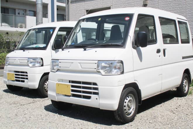 駐車場に並んだ2台の白い軽貨物配送用ワゴン車