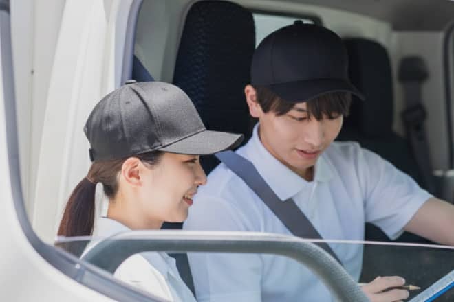 車内で伝票やルートを確認し合う、男女2名の配送スタッフ