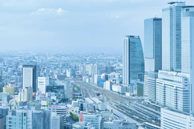 高層ビルが立ち並ぶ大都市の全景と、地上を走る鉄道の線路