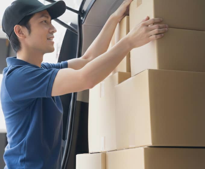 配送用のバンに段ボールを積み込む男性スタッフ。
