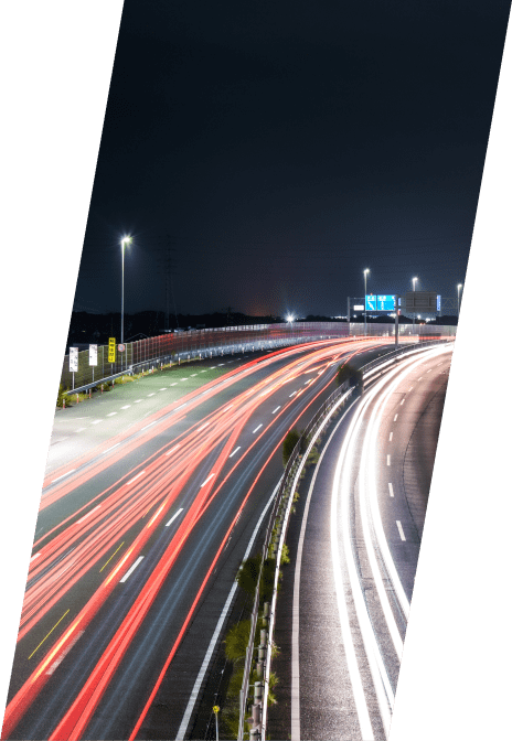 夜間の高速道路を走る車の光跡が、赤と白のラインとなって流れる様子